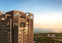 Sattva Sumera Launch Marks Mumbai Debut for Sattva Group Modern brown high-rise with stacked curved arches and rooftop greenery, SATTVA logo, overlooking the coast at sunset.