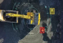 Komatsu Unveils Human Detection System in Crawler Excavators Aerial view of a yellow mining excavator at a pit with digital targeting rings and colored markers indicating sensors or targets nearby