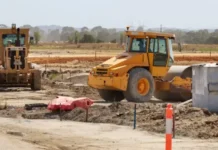 Heavy Equipment Financing Based on the Construction Season Yellow wheel loader at a construction site, moving dirt near a concrete block and pipes.