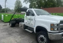 Why Debris Logistics Should Be Part of Preconstruction Planning White pickup truck with ECOBOX logo parked in a lot beside green dumpsters, likely a dumpster rental/service vehicle.